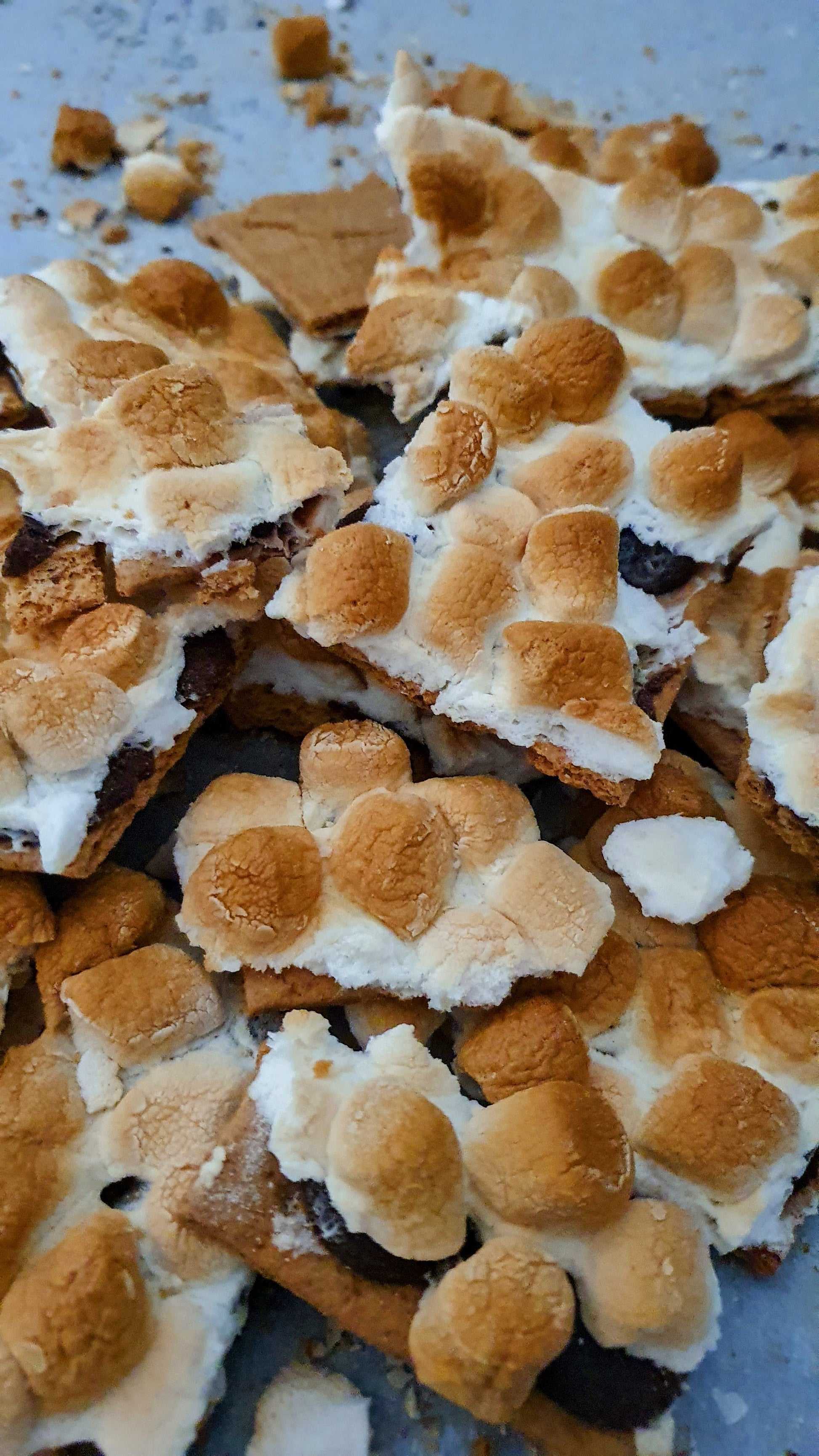 S'mores bark with roasted marshmallows on a metal surface