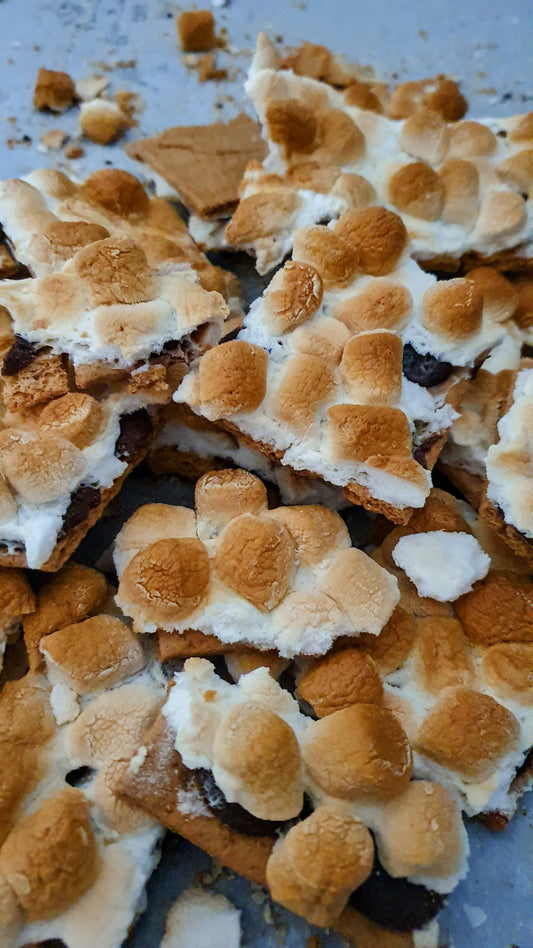 S'mores bark with roasted marshmallows on a metal surface